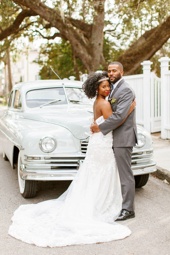 luxury bride and groom with vintage getaway car