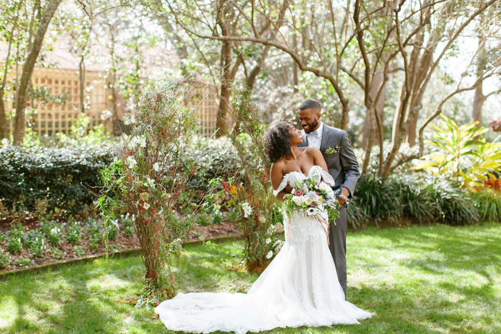 high-end bride and groom with floral arch and bright bouquet